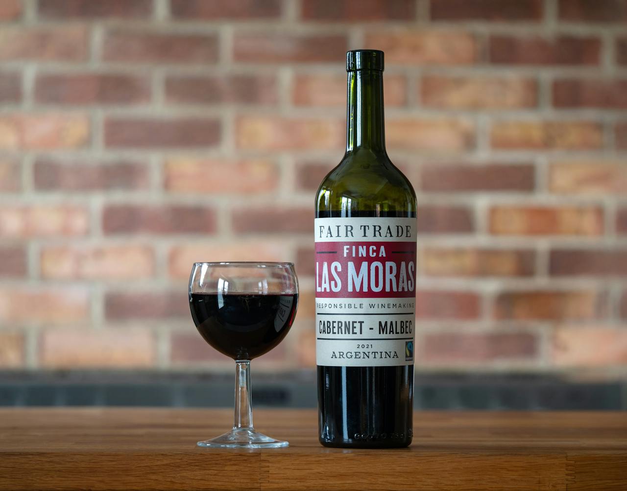A bottle of Finca Las Moras wine with a glass on a wooden table, perfect indoor setting.